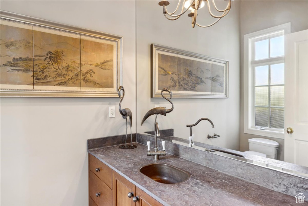 Bathroom featuring toilet, vanity, and a chandelier