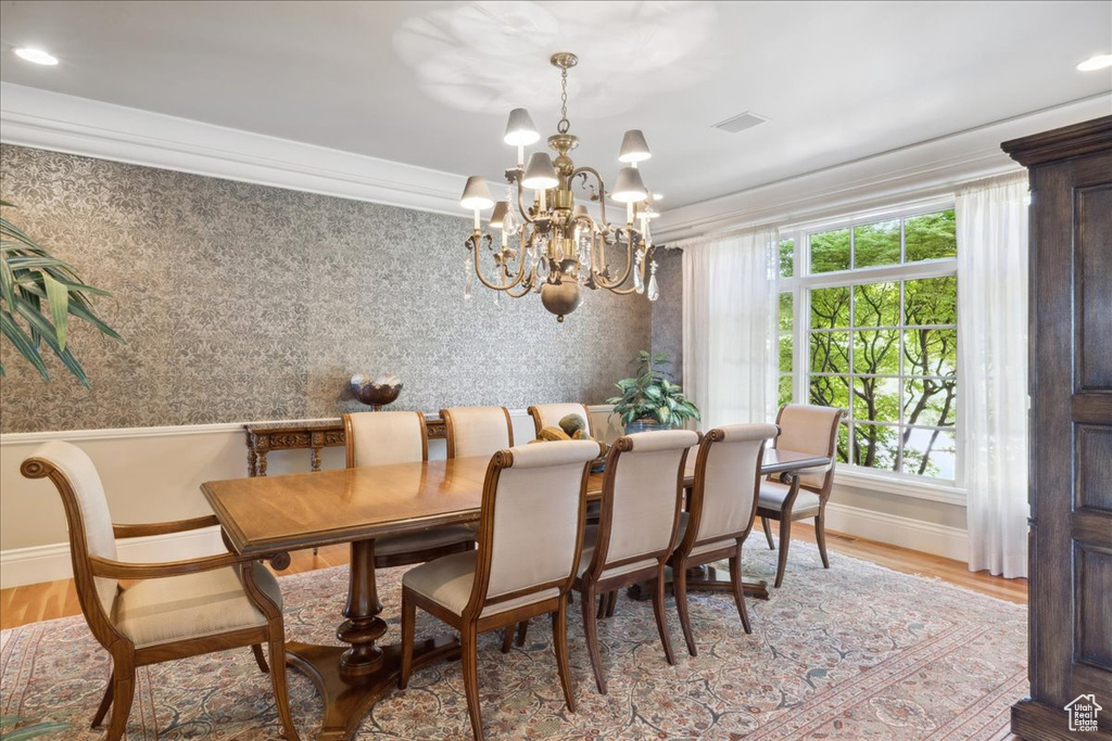 Dining space featuring ornamental molding, a notable chandelier, visible vents, and wood finished floors