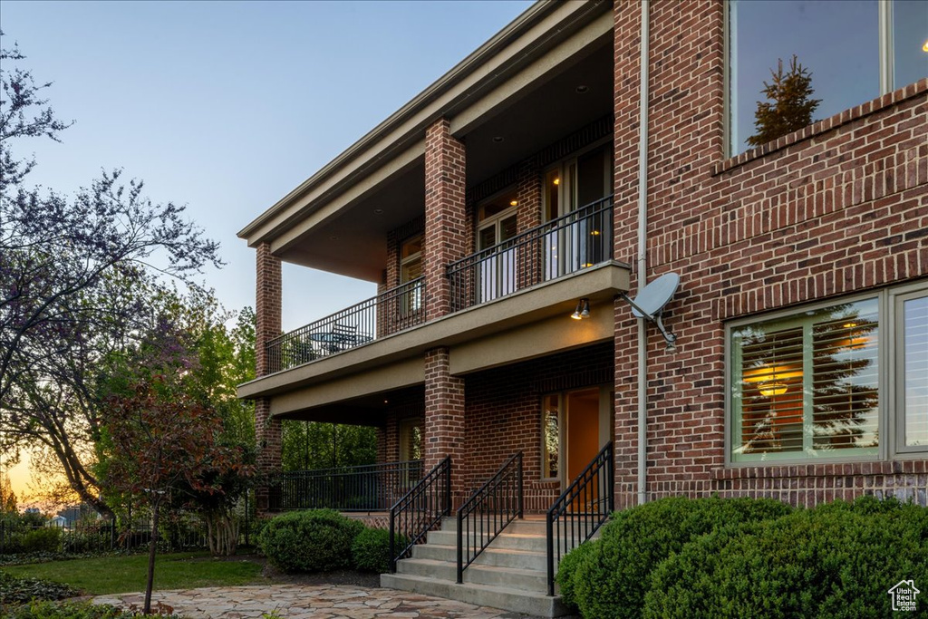 View of front of house with a balcony and brick siding