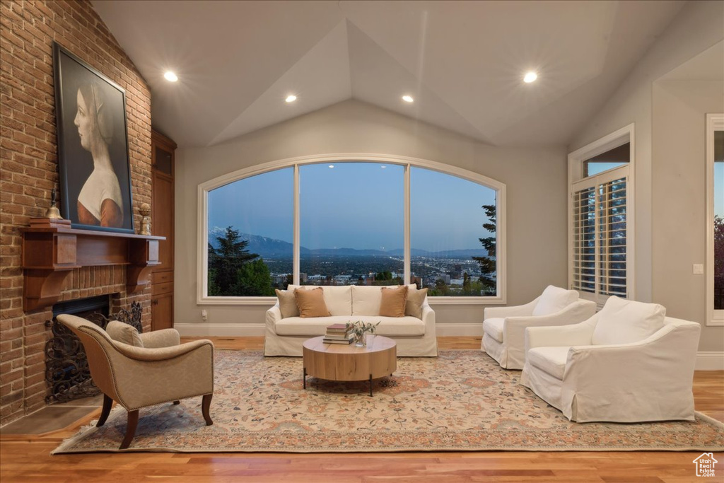 Living area featuring vaulted ceiling, recessed lighting, a brick fireplace, and wood finished floors