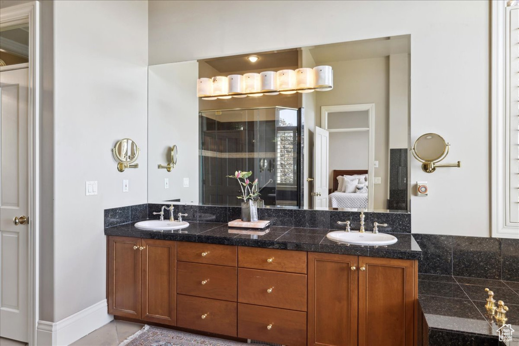 Bathroom featuring double vanity, ensuite bathroom, a shower stall, and a sink