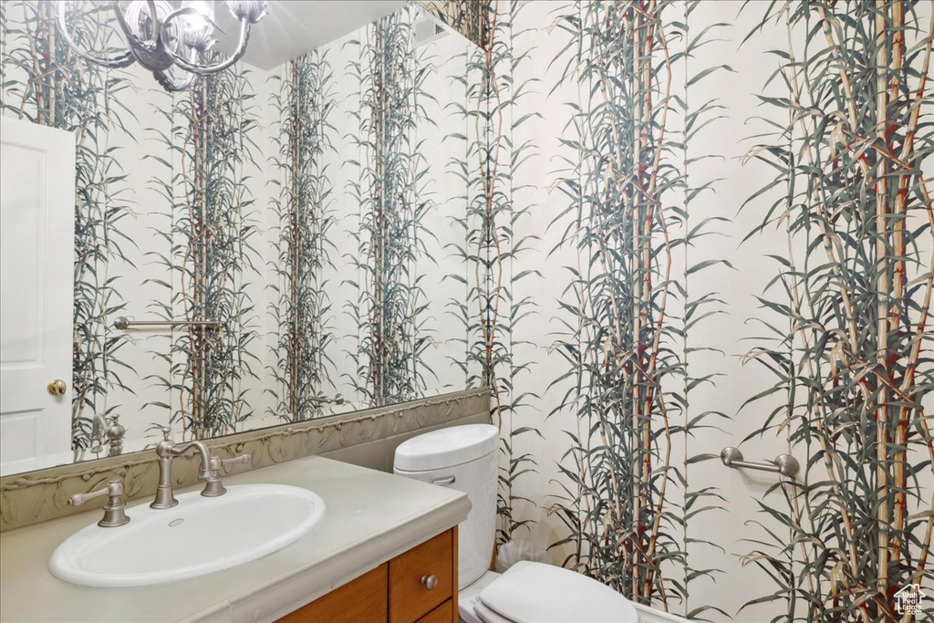 Bathroom featuring toilet, a notable chandelier, and vanity