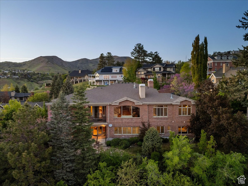 Exterior space with a mountain view, brick siding, a chimney, and a residential view