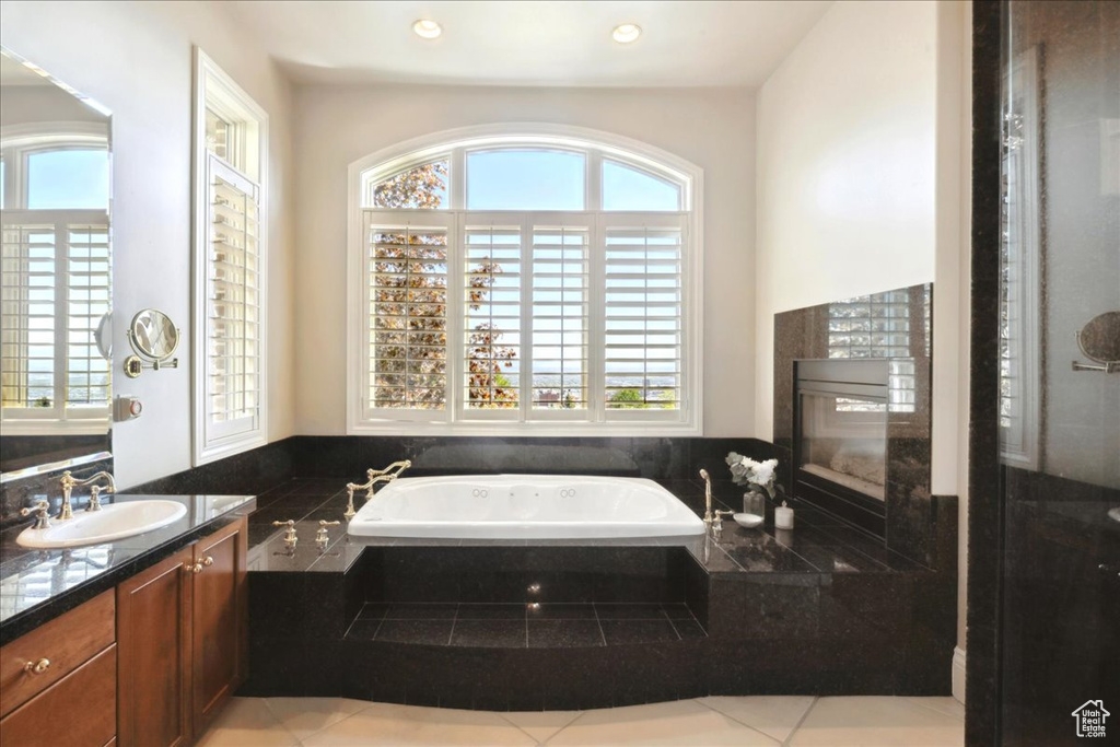 Bathroom featuring a bath, vanity, and plenty of natural light