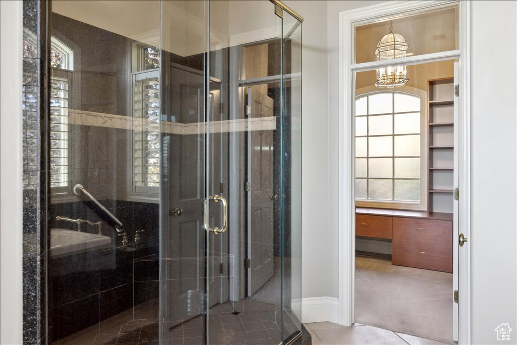Full bathroom featuring a shower stall, a chandelier, and plenty of natural light