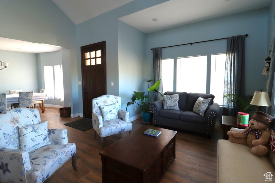 Living area with baseboards, high vaulted ceiling, a notable chandelier, and dark wood finished floors