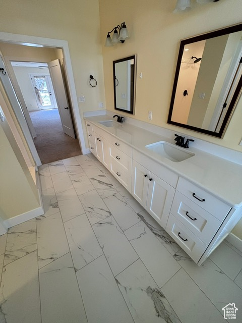 Bathroom with marble finish flooring, baseboards, and double vanity