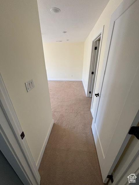 Hallway with carpet flooring and baseboards