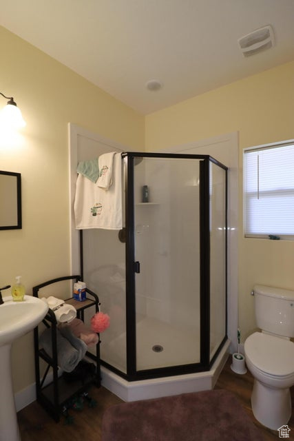 Bathroom with a stall shower, toilet, visible vents, and wood finished floors