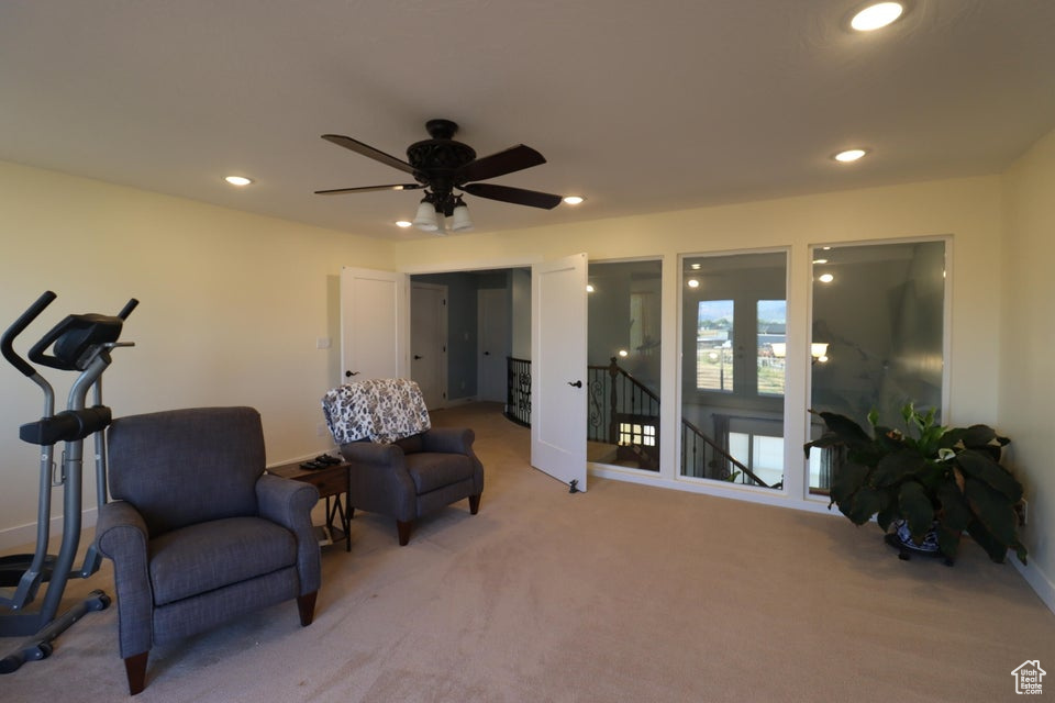 Sitting room with light carpet, an upstairs landing, and recessed lighting