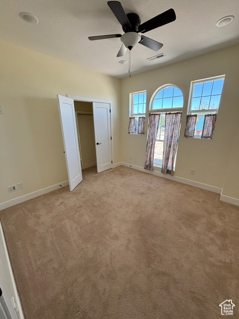 Unfurnished bedroom featuring light colored carpet, baseboards, and a ceiling fan