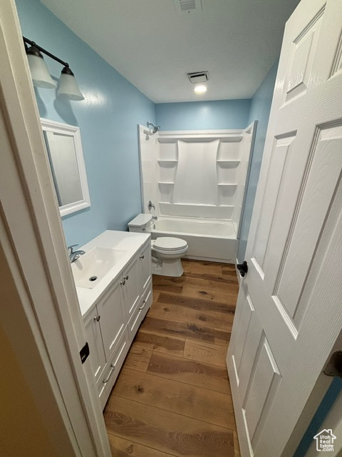 Full bath with wood finished floors, vanity, bathtub / shower combination, and toilet