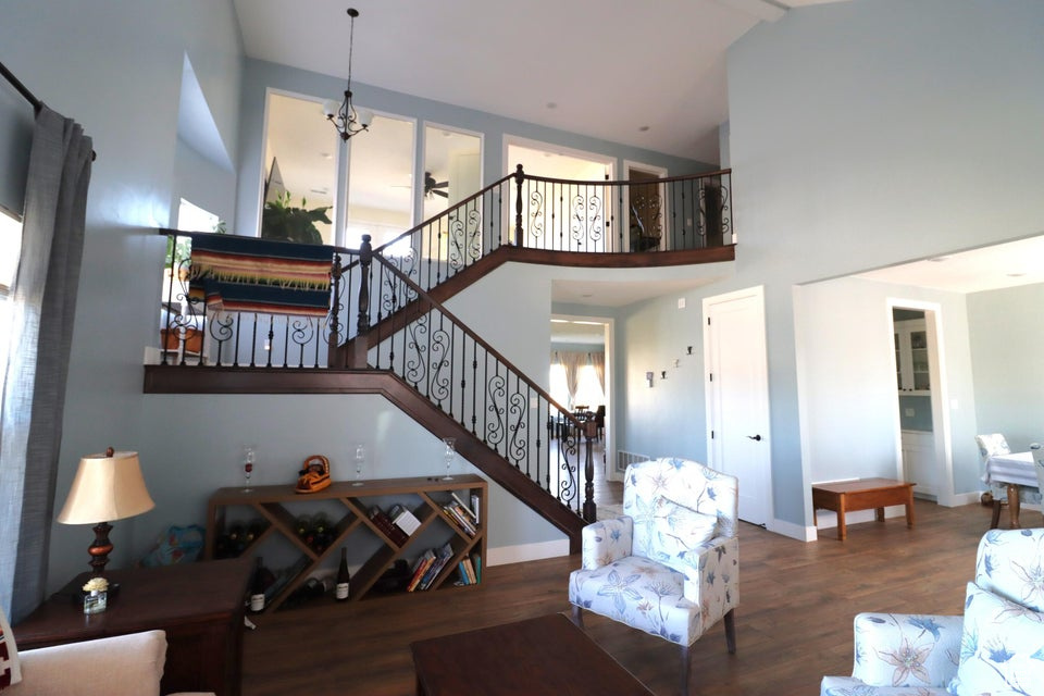 Living room with high vaulted ceiling, wood finished floors, baseboards, and stairs