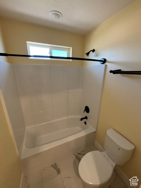 Full bath with toilet, marble finish floors, baseboards, and tub / shower combination