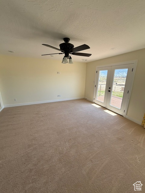 Unfurnished room with french doors, a textured ceiling, light colored carpet, a ceiling fan, and baseboards