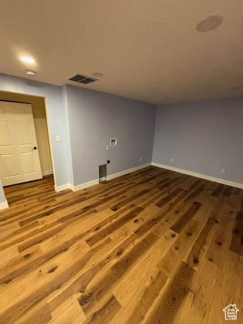 Unfurnished room with wood finished floors, baseboards, and a textured ceiling