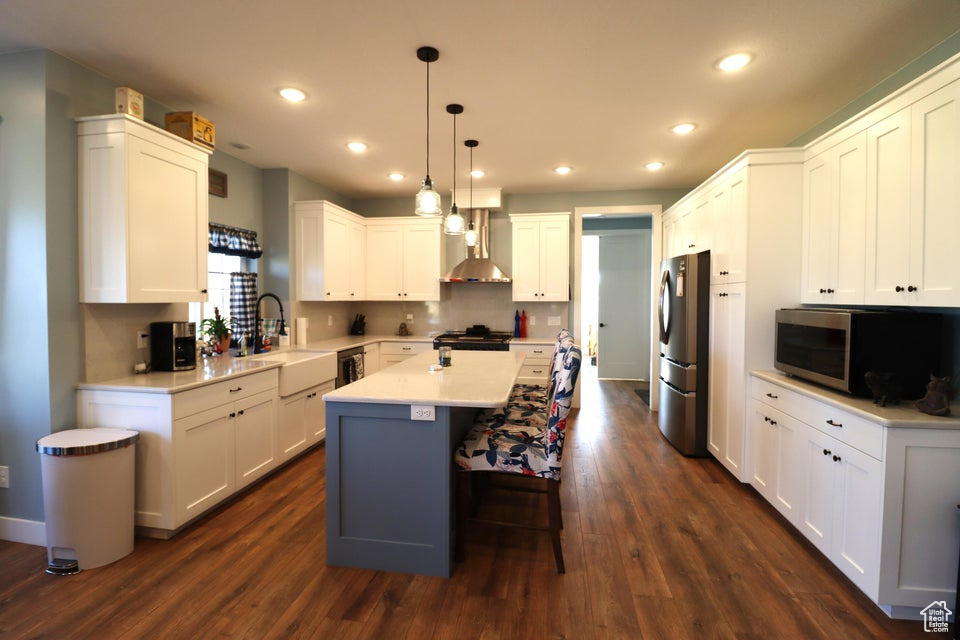 Kitchen featuring recessed lighting, a center island, a sink, wall chimney range hood, and stainless steel appliances