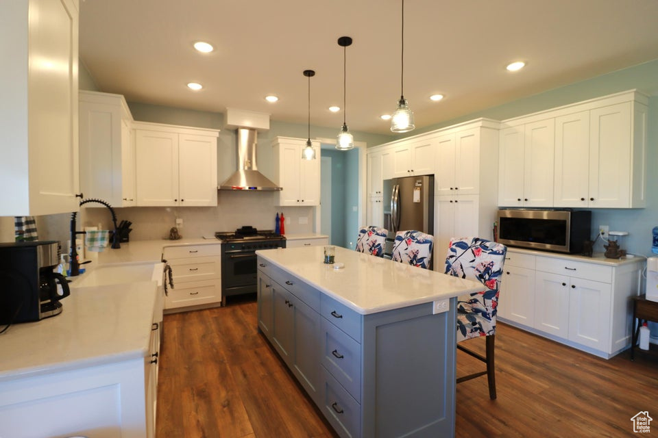 Kitchen featuring stainless steel appliances, white cabinets, gray cabinets, and wall chimney exhaust hood