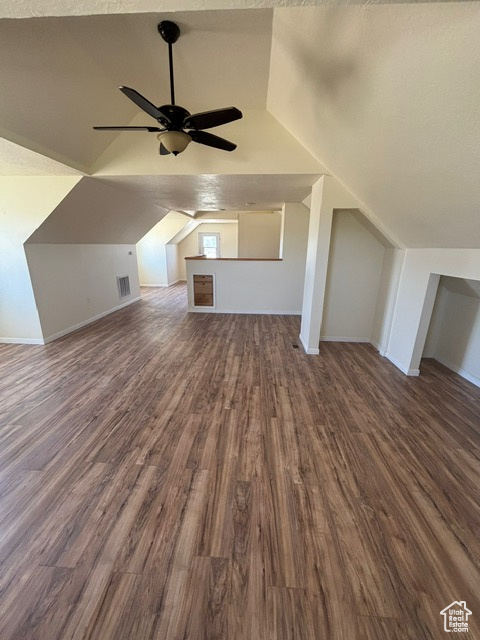 Additional living space featuring ceiling fan, vaulted ceiling, dark wood-style flooring, and baseboards