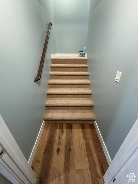 Stairway with wood finished floors and baseboards