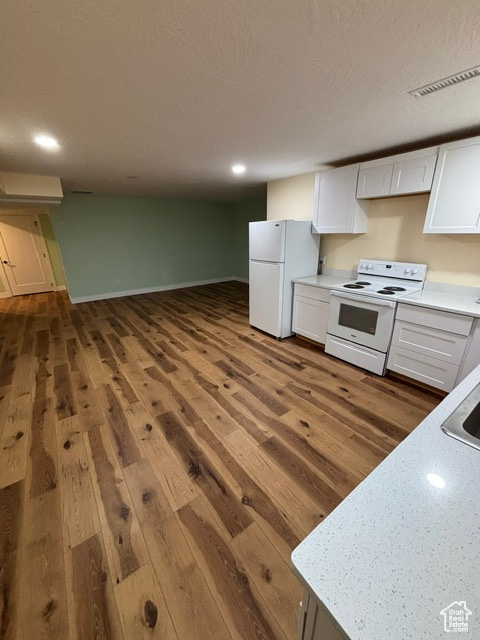 Kitchen with white appliances, white cabinets, dark wood-style floors, light countertops, and recessed lighting