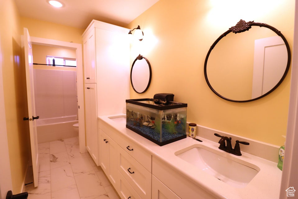 Full bath featuring a sink, marble finish floor, recessed lighting, double vanity, and bathtub / shower combination