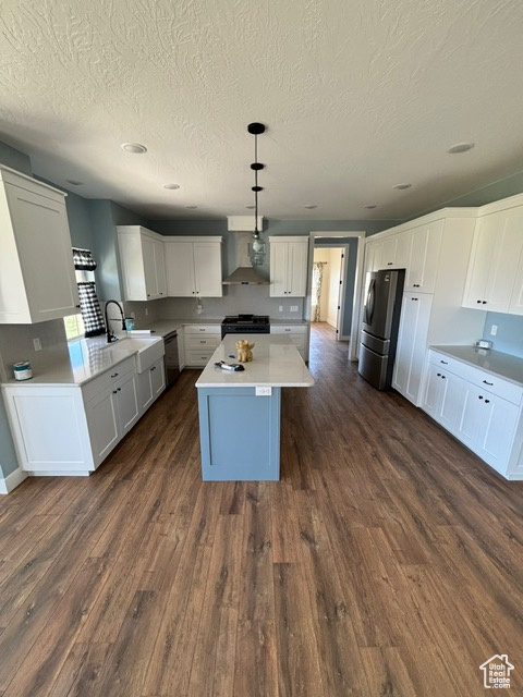 Kitchen featuring freestanding refrigerator, dishwashing machine, black range with gas stovetop, a kitchen island, and dark wood-type flooring