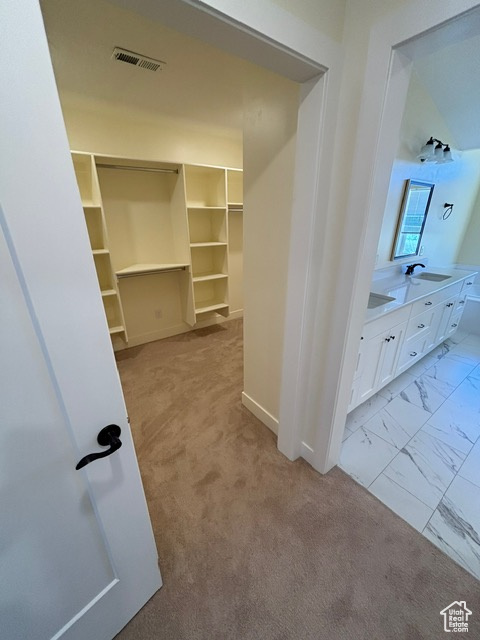 Walk in closet featuring a sink, light marble finish floors, and light carpet