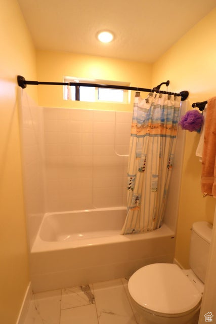 Bathroom featuring toilet, marble finish floor, recessed lighting, shower / bath combo, and baseboards