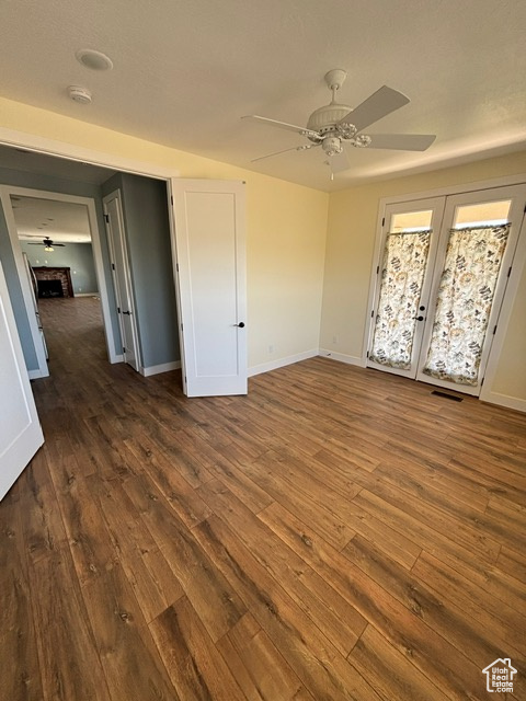 Unfurnished bedroom with dark wood-style floors, baseboards, and a ceiling fan