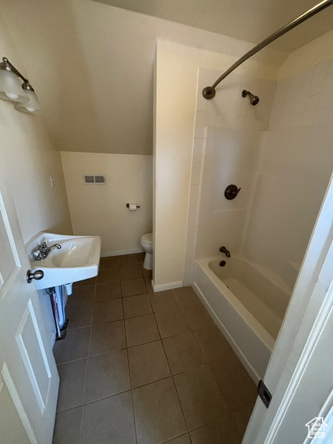 Full bath featuring tile patterned floors, toilet, vaulted ceiling, and bathing tub / shower combination