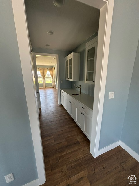 Corridor with baseboards, dark wood-type flooring, a sink, and recessed lighting