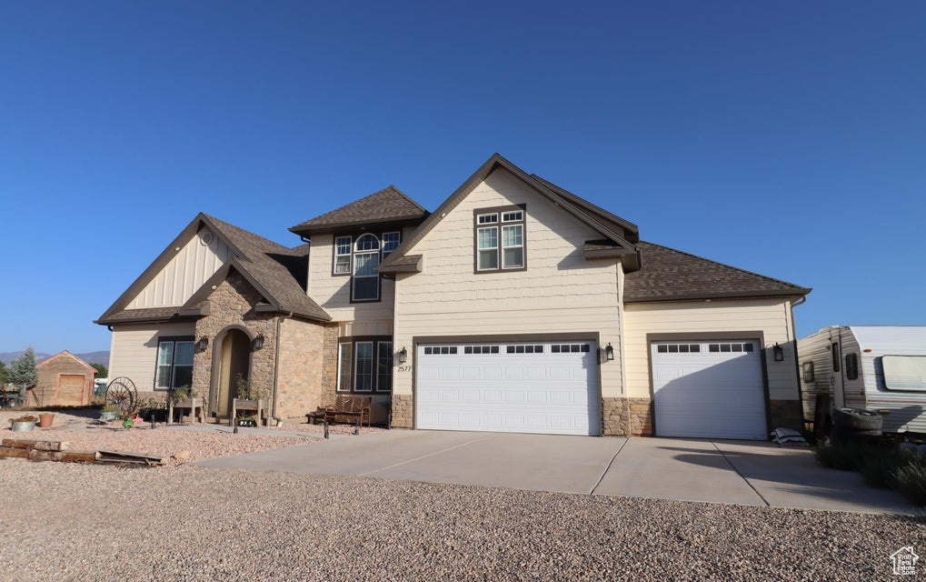 View of front of house with roof with shingles, stone siding, concrete driveway, a garage, and board and batten siding
