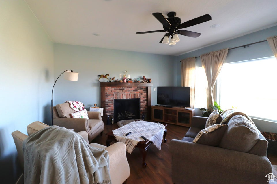Living room featuring wood finished floors, a fireplace, and ceiling fan