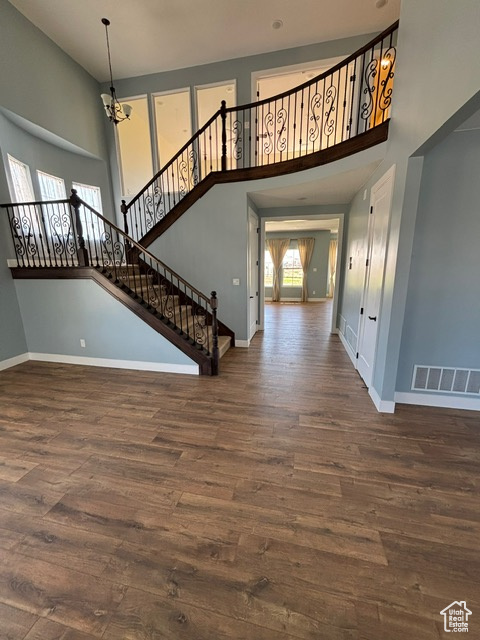 Entryway featuring a towering ceiling, wood finished floors, baseboards, and stairway