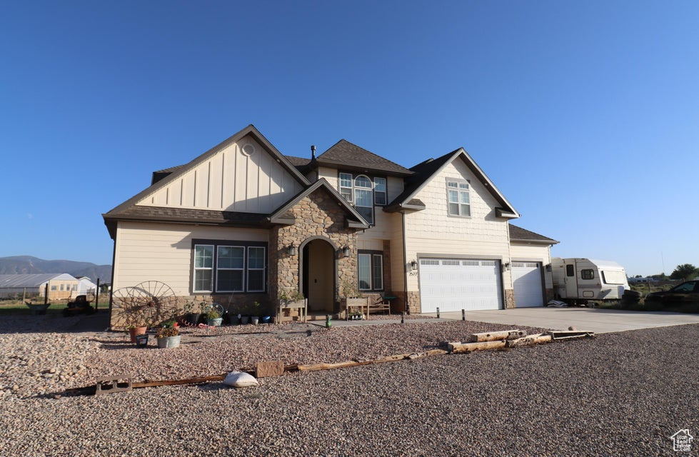 Craftsman house featuring driveway, an attached garage, stone siding, and board and batten siding