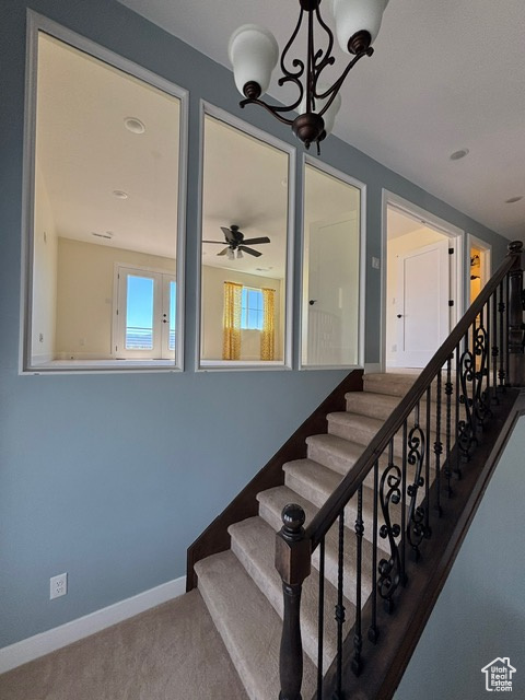 Stairway with carpet flooring, baseboards, a ceiling fan, and a chandelier