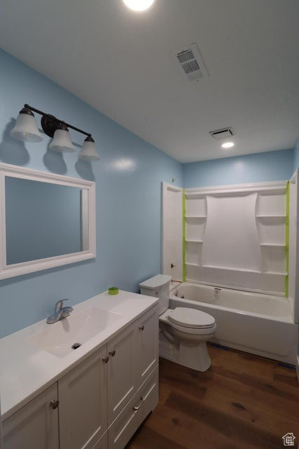 Full bath with toilet, wood finished floors, shower / bathing tub combination, visible vents, and vanity