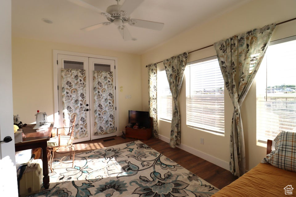 Bedroom with baseboards, multiple windows, ceiling fan, and wood finished floors