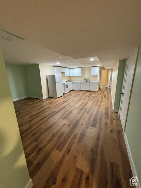 Unfurnished living room with dark wood-type flooring, baseboards, and recessed lighting