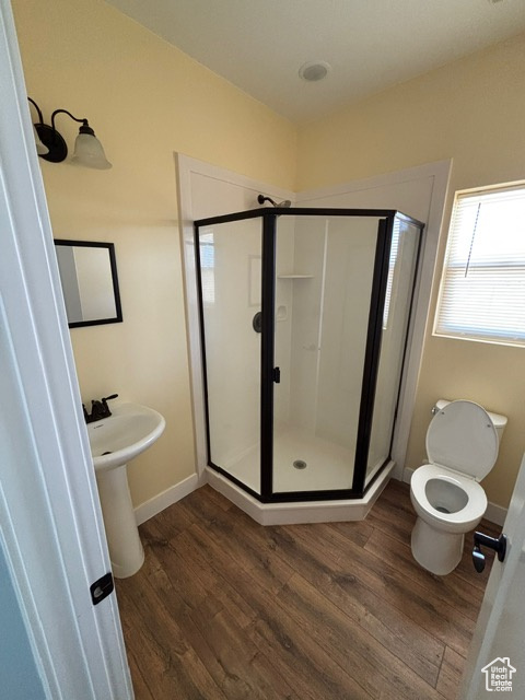 Full bath featuring wood finished floors, a stall shower, and baseboards