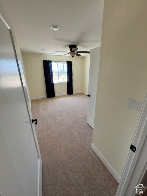 Hallway featuring light carpet and baseboards