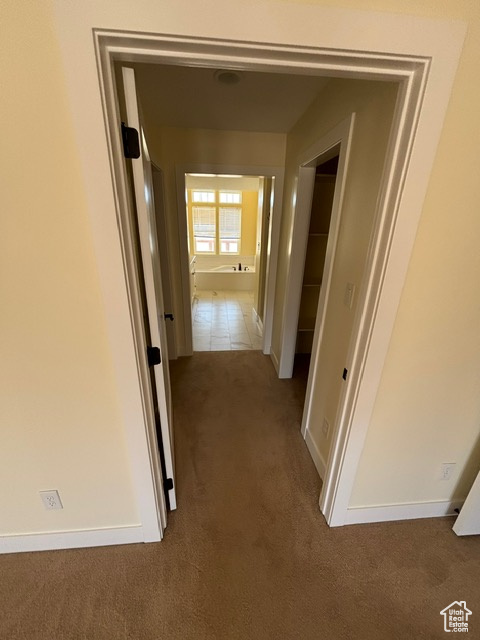 Hallway featuring carpet and baseboards