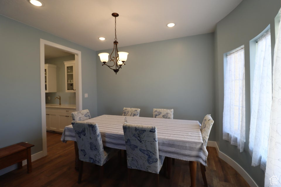 Dining area featuring an inviting chandelier, dark wood finished floors, baseboards, and recessed lighting