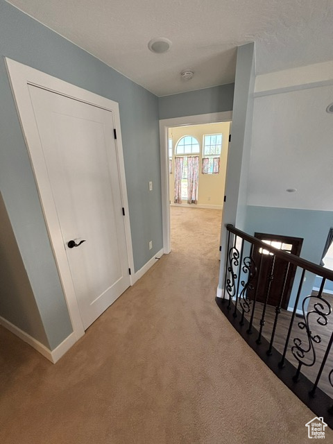 Hall featuring an upstairs landing, carpet flooring, and baseboards