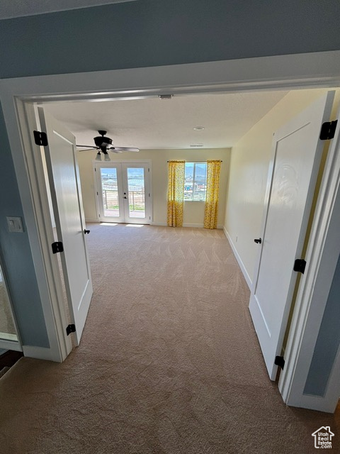 Hall with light colored carpet and baseboards