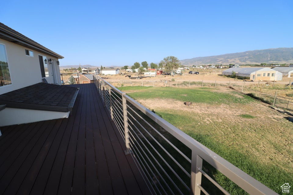 Wooden deck with fence, a mountain view, and a lawn
