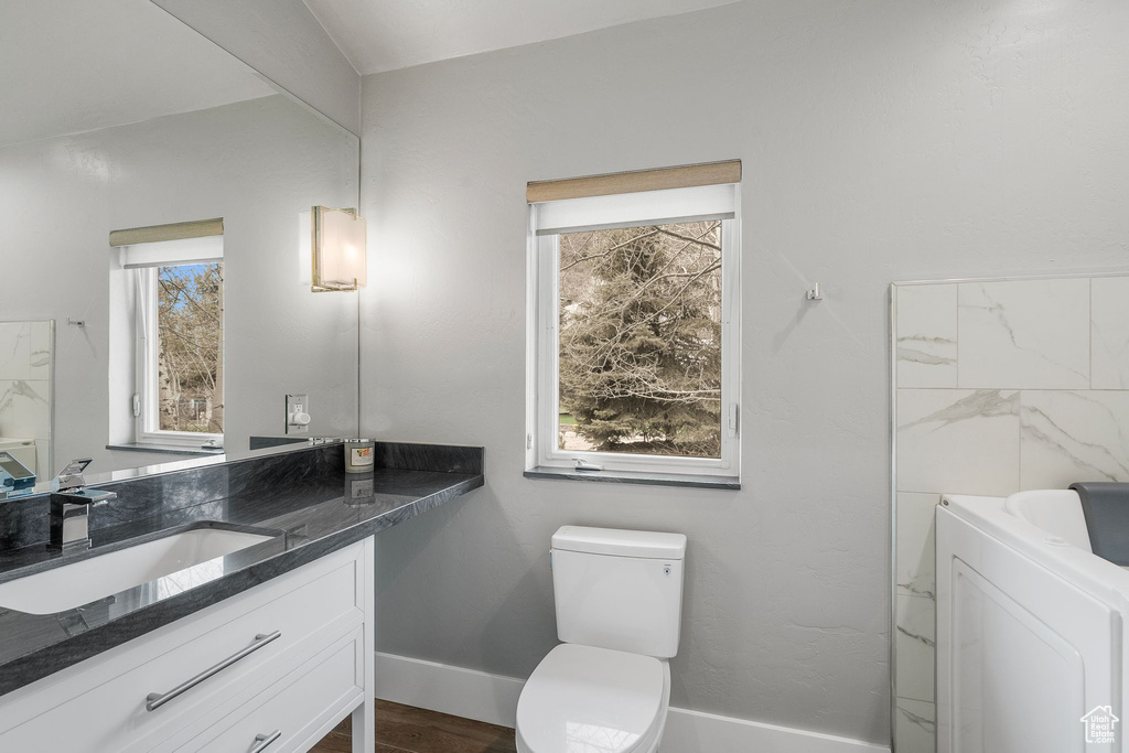 Bathroom featuring toilet, baseboards, washer / dryer, vanity, and wood finished floors
