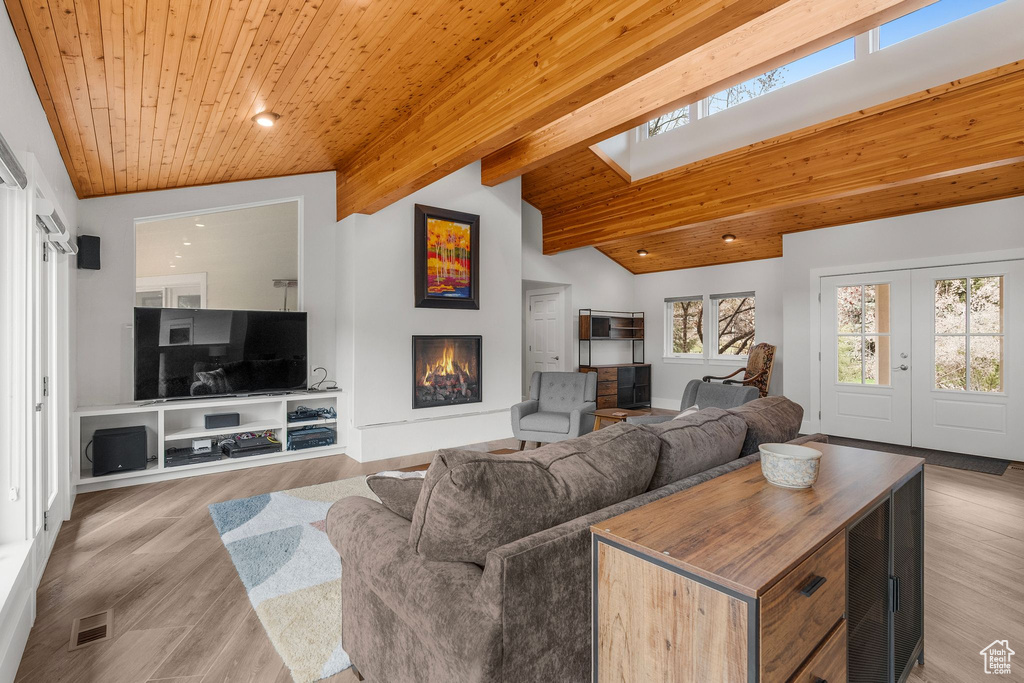Living area with a lit fireplace, lofted ceiling with skylight, wood ceiling, and visible vents