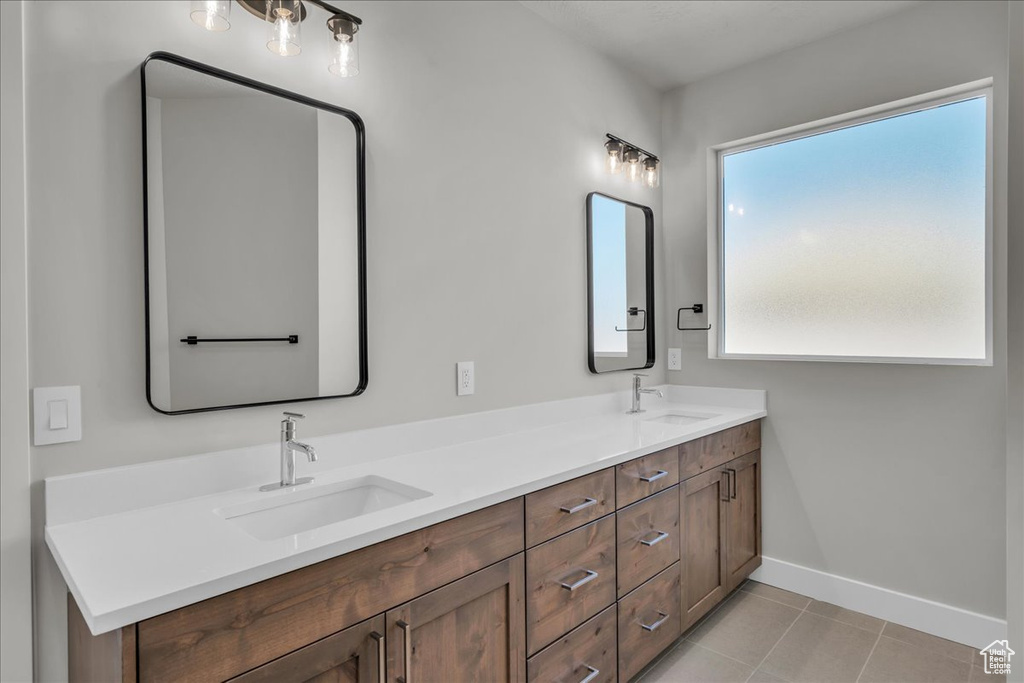 Bathroom featuring a sink, double vanity, baseboards, and tile patterned floors
